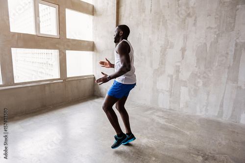 Well-built african guy making warm-up exercises