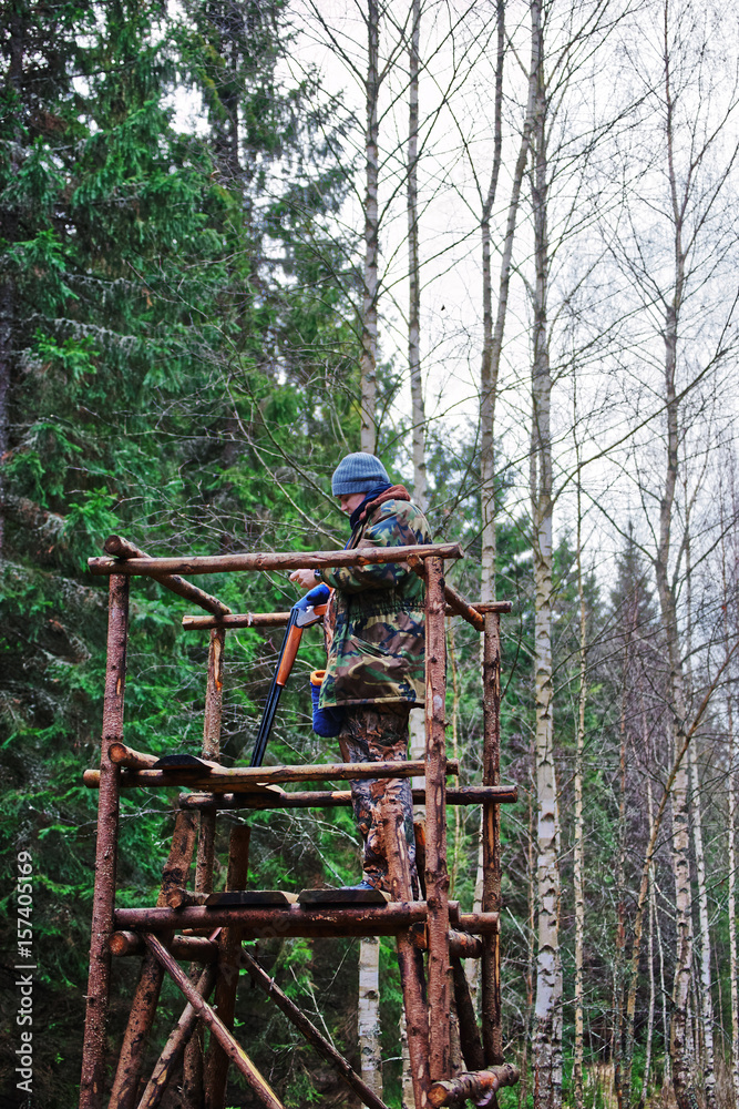 Male hunter on watch tower in autumn forest