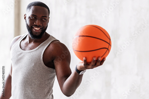Joyful bearded handsome athlete offering others to practice ball game
