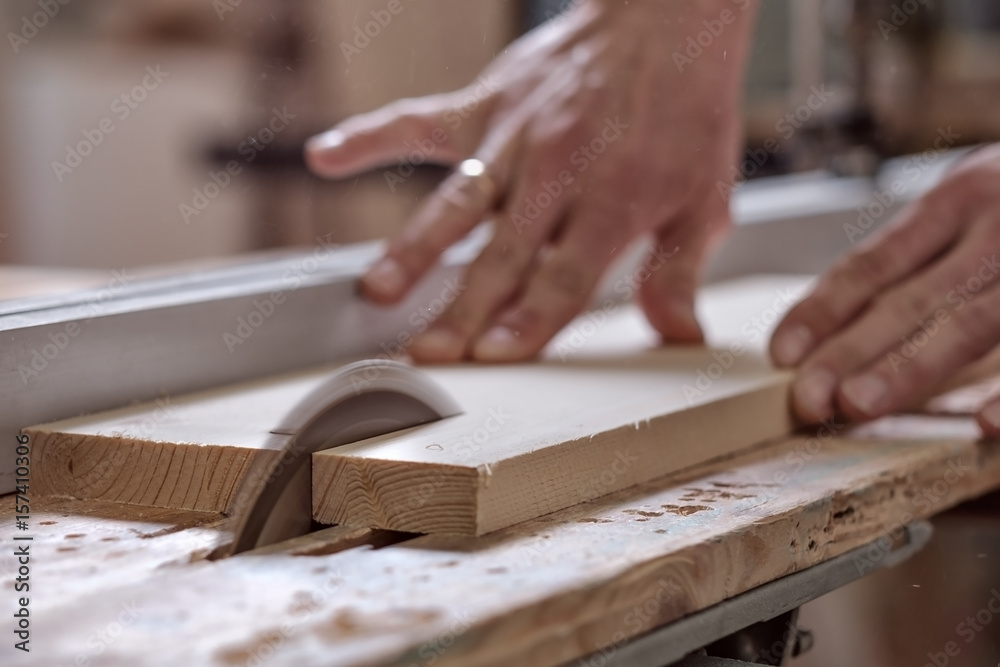 The joiner saws a piece of wood in 2 parts on with electric tool The joiner saws a piece of wood in 2 parts on with electric tool