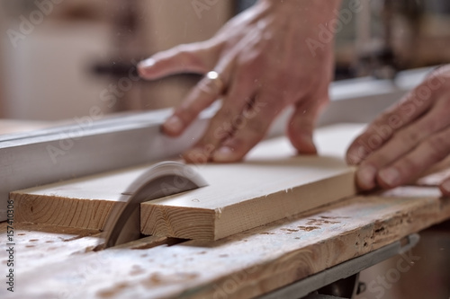 The joiner saws a piece of wood in 2 parts on with electric tool