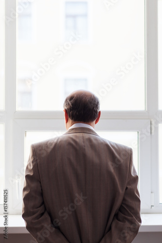 Portrait of a man in a suit by the window. Snapshot from the back
