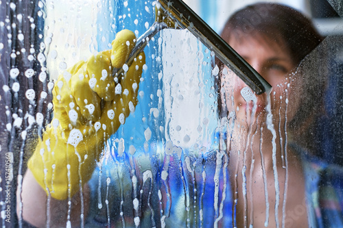A girl washes windows at home. To clean up the house. photo