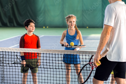 Male tennis trainer teaching children