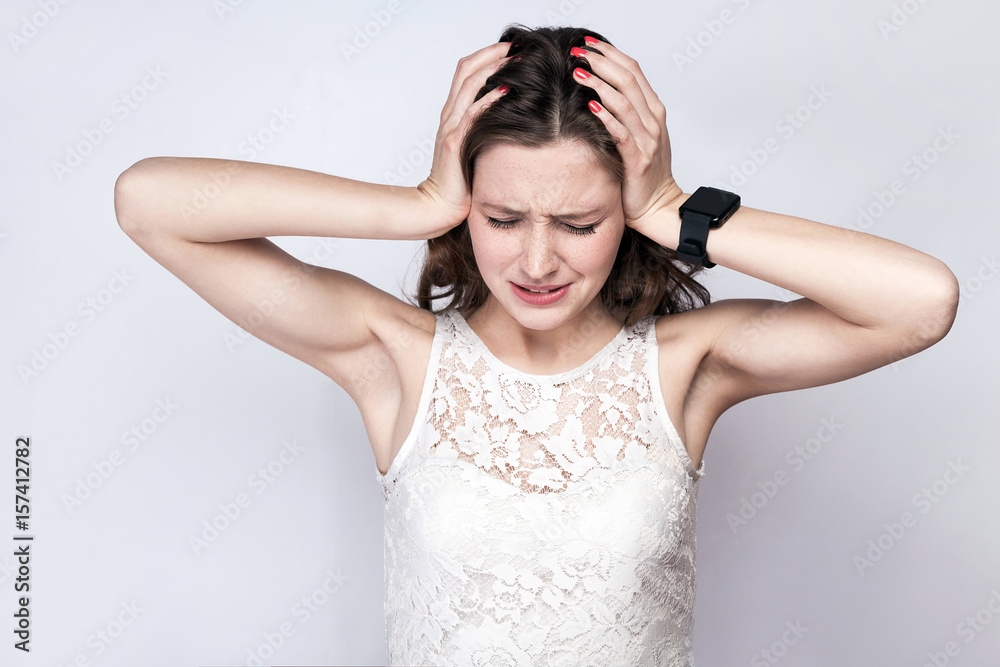 Portrait of beautiful woman with freckles and white dress and smart watch with headache pain on silver gray background. healthcare and medicine concept. Portrait of beautiful woman with freckles and white dress and smart watch with headache pain on silver gray background. healthcare and medicine concept.