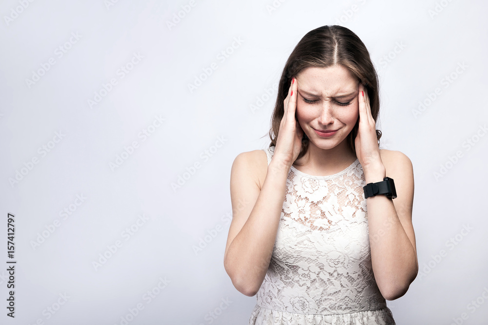 Portrait of beautiful woman with freckles and white dress and smart watch with headache pain on silver gray background. healthcare and medicine concept. Portrait of beautiful woman with freckles and white dress and smart watch with headache pain on silver gray background. healthcare and medicine concept.