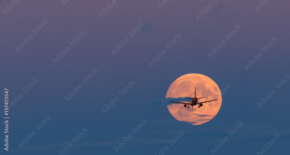 Obraz premium Silhouette of landing airplane at moon rise