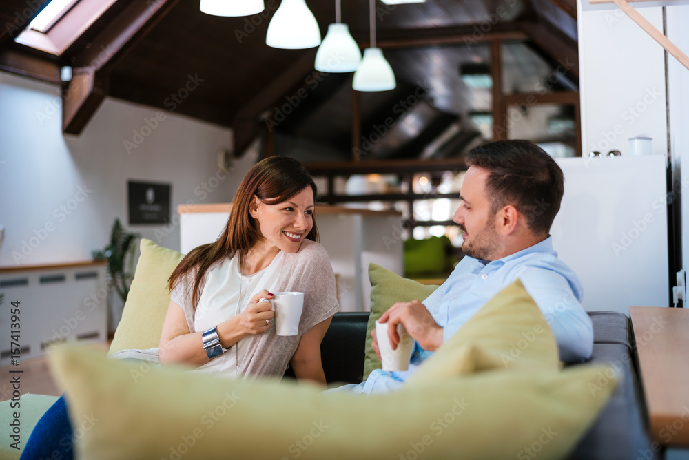 Couple at home relaxing in lounge with hot drink Couple at home relaxing in lounge with hot drink