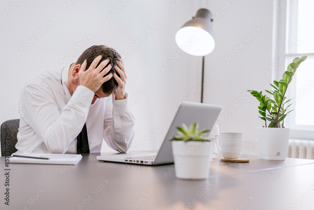 Frustrated middle aged businessman sitting at office desk Frustrated middle aged businessman sitting at office desk