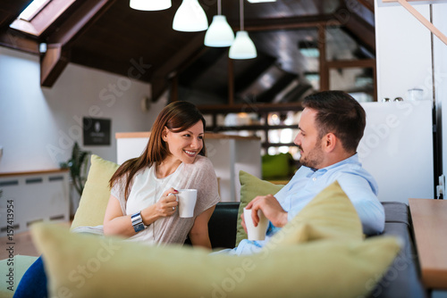 Couple at home relaxing in lounge with hot drink