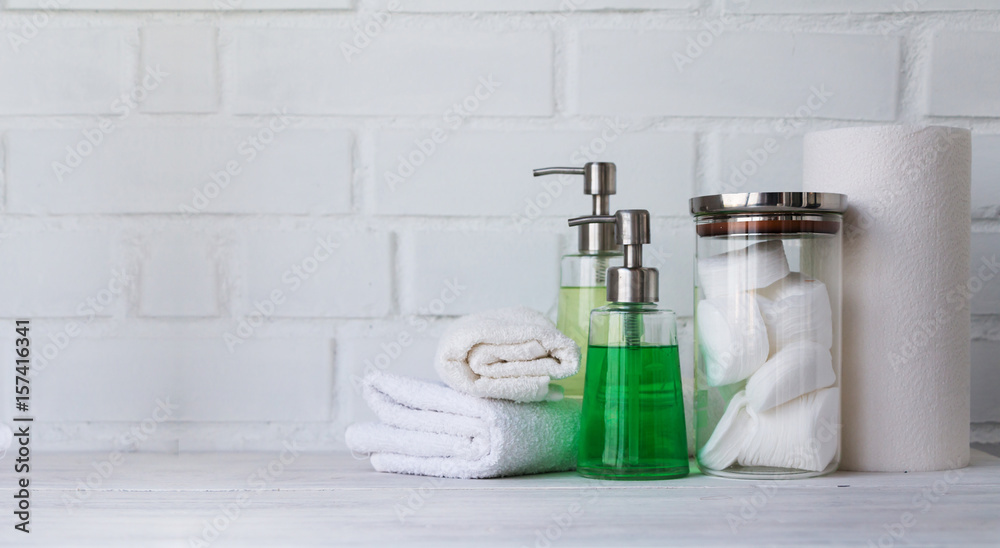 Part of spa interior. Cotton napkins, cotton pads, tissue, towels, soap and cosmetic products on a wooden table. White background and table. Copy space. Selective focus. Part of spa interior. Cotton napkins, cotton pads, tissue, towels, soap and cosmetic products on a wooden table. White background and table. Copy space. Selective focus.