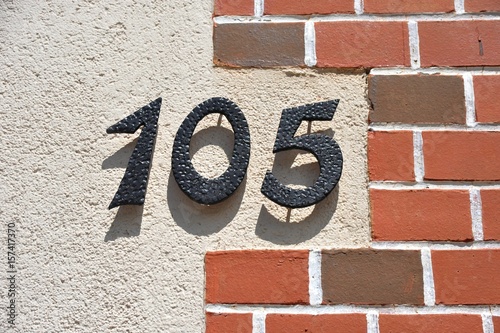 Hausnummer 105 aus gehämmertem Stahl an einer Ziegelwand