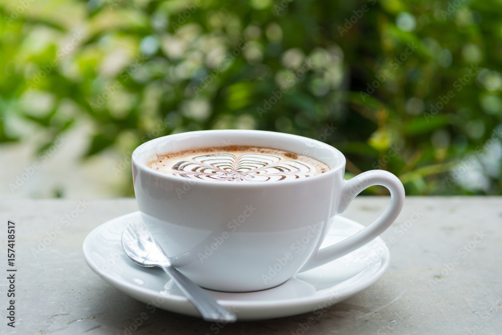 Cappuccino art cup of coffee with bokeh of trees view Cappuccino art cup of coffee with bokeh of trees view