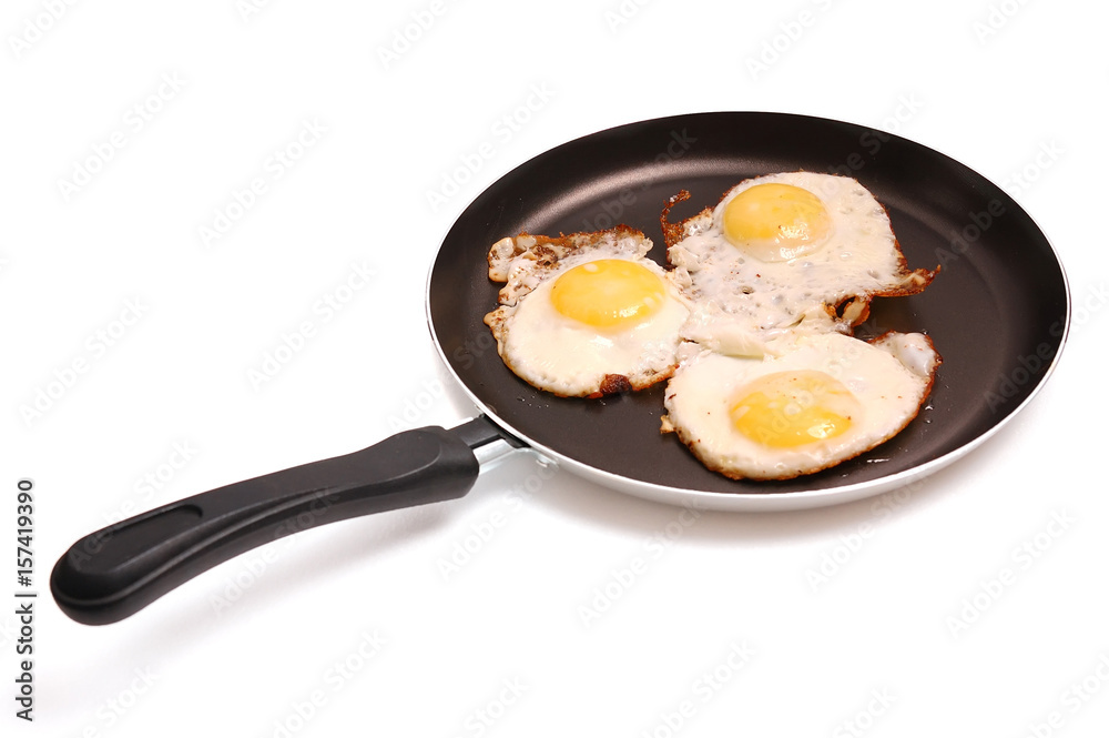 The frying pan with fried eggs isolated on the white The frying pan with fried eggs isolated on the white