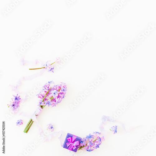 Bouquet of pink flowers, paper box and shabby tapes on white background. Flat lay, top view. Holidays background