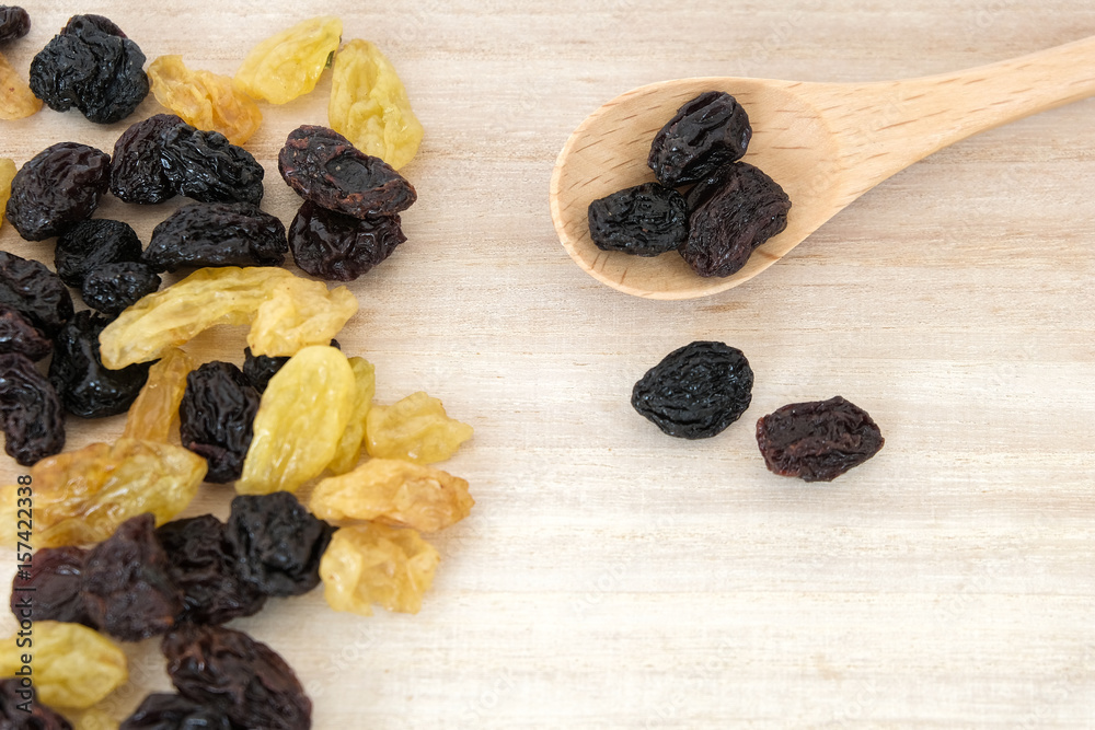Dried raisins in wooden spoon on wood table. Dried raisins in wooden spoon on wood table.