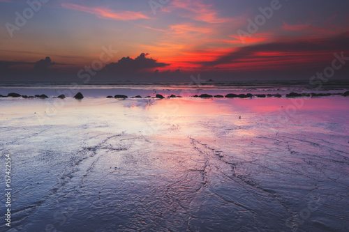 The ocean retreat during low tide leaving puddle of water which caused reflection during sunset.