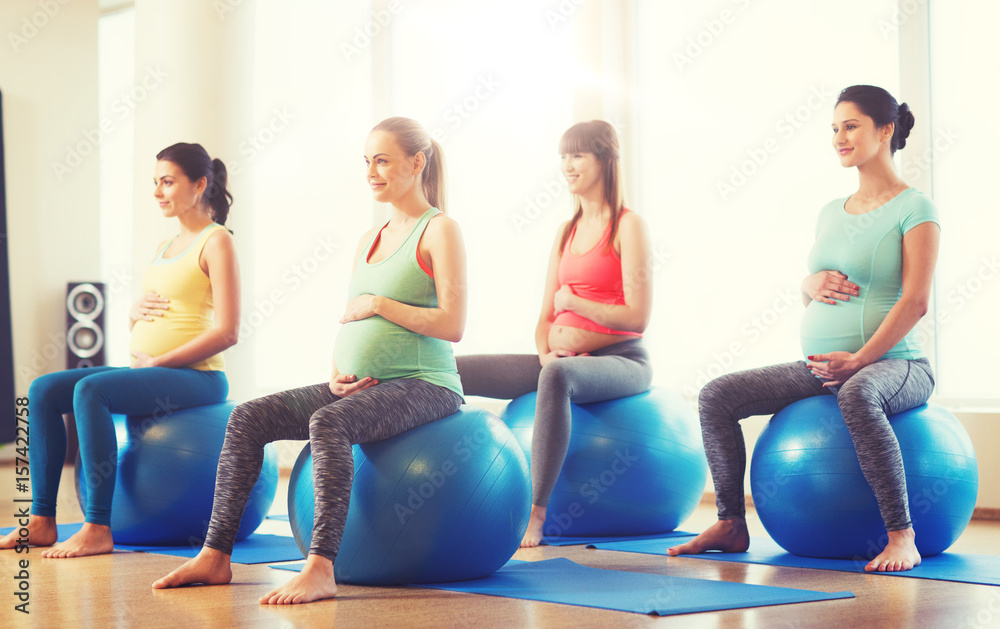 happy pregnant women exercising on fitball in gym happy pregnant women exercising on fitball in gym
