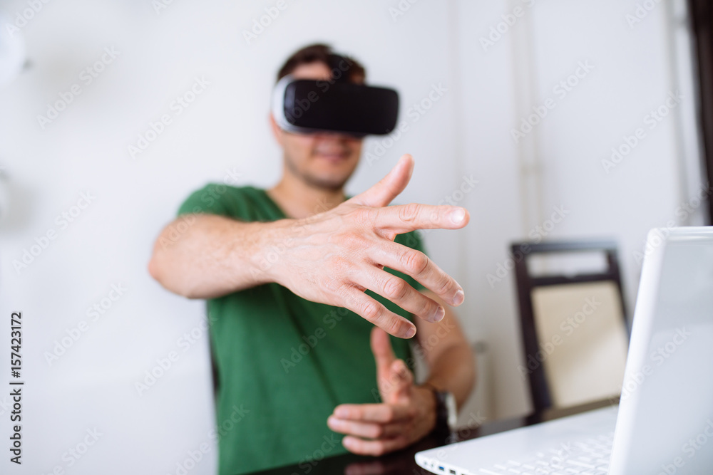 Young man with virtual reality goggles. Selective focus on hands and VR glasses.
