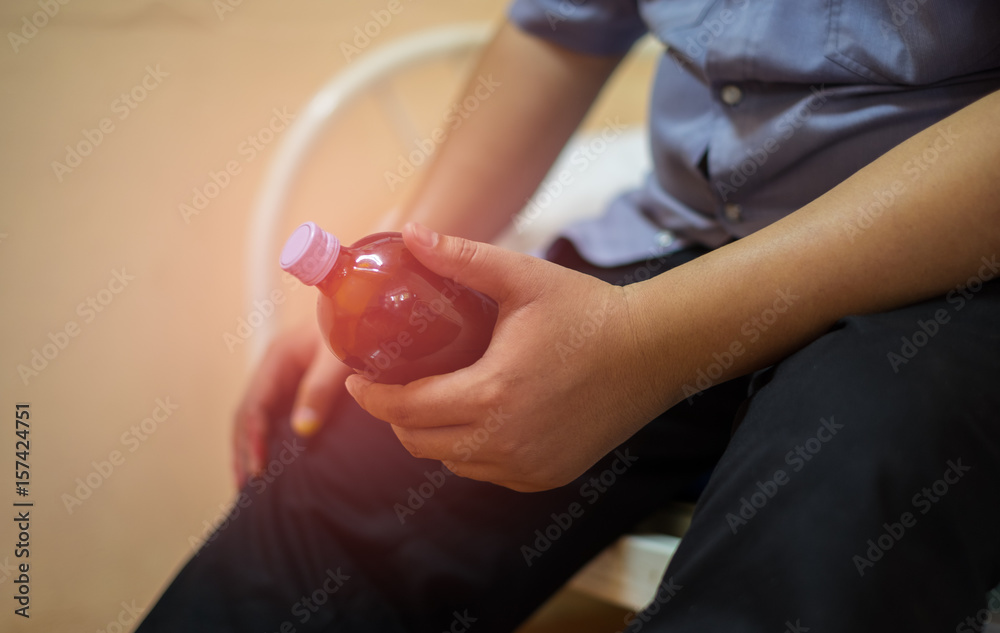 Naklejka premium A Fat man sits and holding a bottle of medicine for himself on the bed. He has heart disease. Health care concept. Close-up