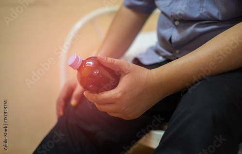 A Fat man sits and holding a bottle of medicine for himself on the bed. He has heart disease. Health care concept. Close-up