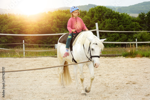 Kind bei Reitunterricht in Reitschule reitet auf Pferd