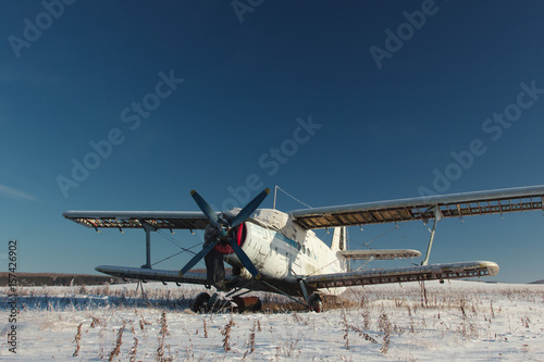 Old plane on parking in the middle of the winter field.