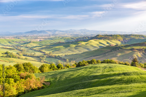 Rural rolling landscape view with fields and groves of trees in a valley in Tuscany