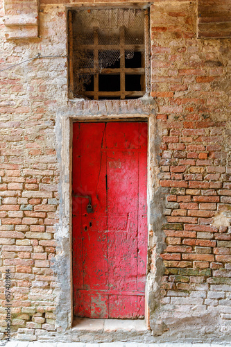 Old weathered red wooden door in an alley