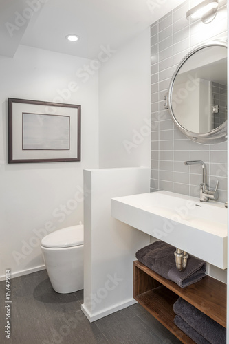 Shot of clean modern bathroom with tiled wall and round mirror