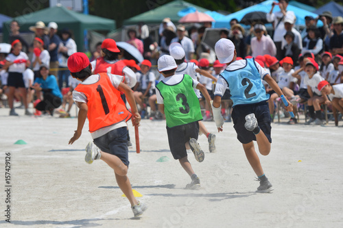 小学校の運動会のリレーで競争する子供たち