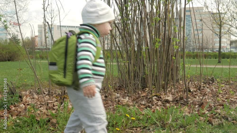 Toddler boy playing in the park with mom in the spring. He runs around and looks around. Moving camera Toddler boy playing in the park with mom in the spring. He runs around and looks around. Moving camera