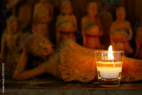 Aroma candle placed in front of handcraft wooden statue of reclining buddha
