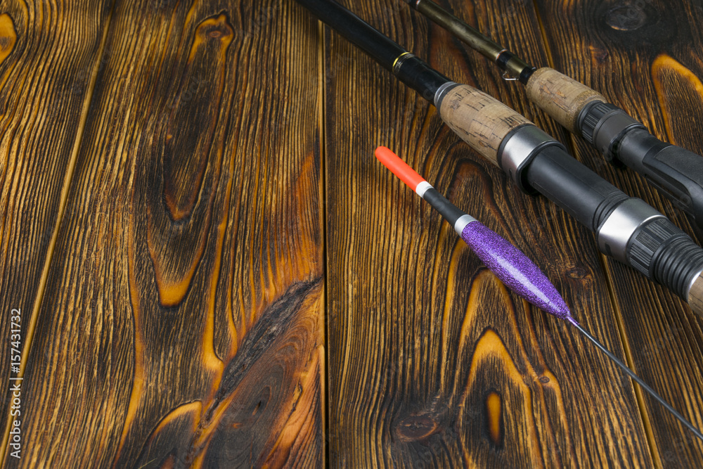 Naklejka premium Fishing tackle - fishing rod fishing float and lures on beautiful wooden background