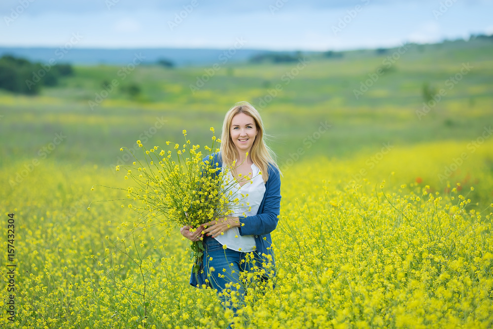Genuine cute lady woman in meadow of yellow flowers sniffing flower bouquet. Attractive beautiful young girl enjoying the warm summer sun in a wide green and yellow meadow. Stylish dressed Genuine cute lady woman in meadow of yellow flowers sniffing flower bouquet. Attractive beautiful young girl enjoying the warm summer sun in a wide green and yellow meadow. Stylish dressed