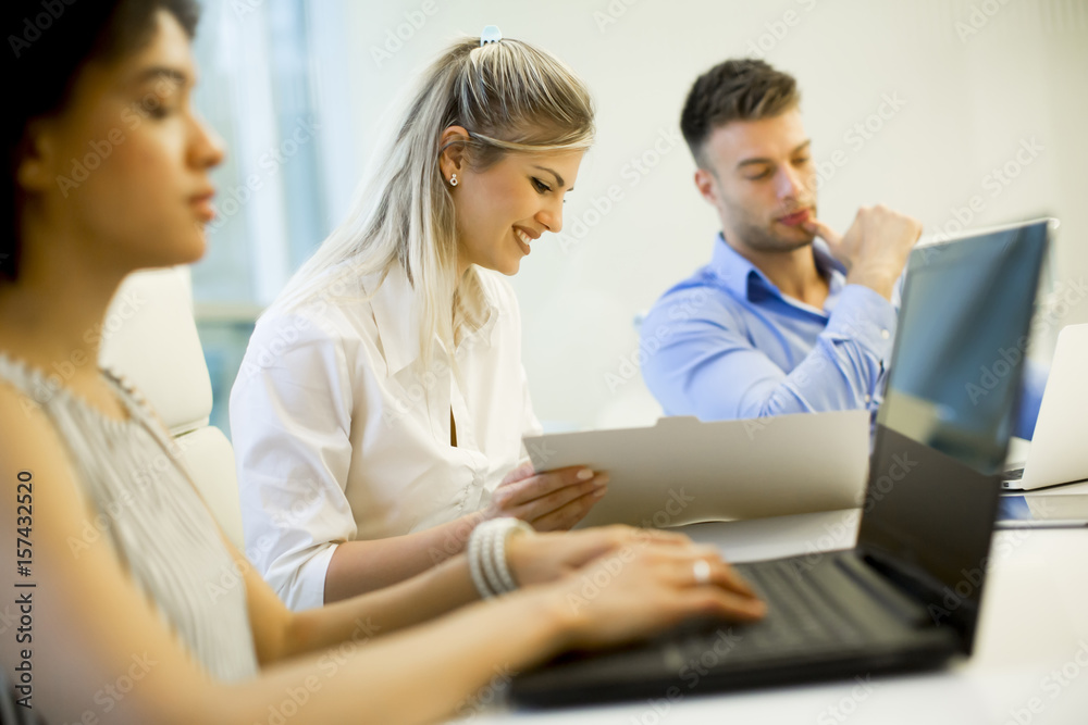 Young business people using laptop and smiling while working in office Young business people using laptop and smiling while working in office