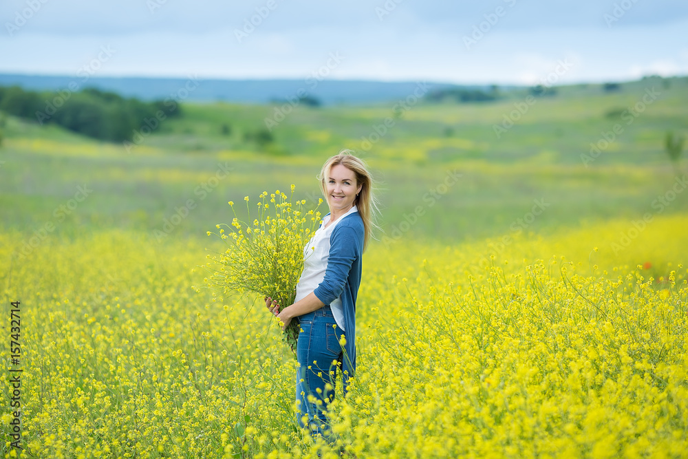 Genuine cute lady woman in meadow of yellow flowers sniffing flower bouquet. Attractive beautiful young girl enjoying the warm summer sun in a wide green and yellow meadow. Stylish dressed Genuine cute lady woman in meadow of yellow flowers sniffing flower bouquet. Attractive beautiful young girl enjoying the warm summer sun in a wide green and yellow meadow. Stylish dressed