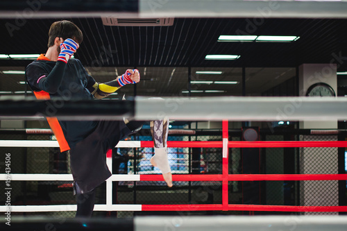 Professional Muay Thai fighter. Male boxer in training sportswear, an exercise in sports hall, fight with a shadow in ring, Strike testing © evgeniykleymenov