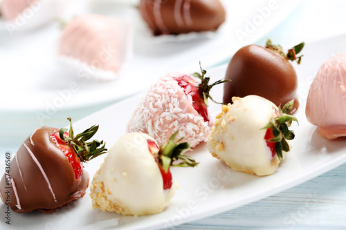 фотографія Strawberries covered in chocolate on a blue wooden table