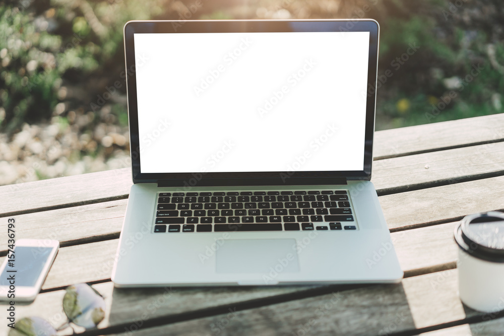Mockup image of laptop with blank white screen on vintage wooden table in outdoor cafe Mockup image of laptop with blank white screen on vintage wooden table in outdoor cafe