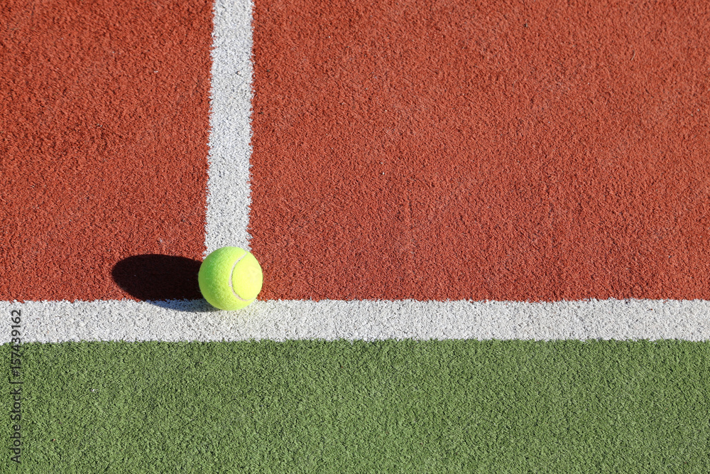Gelber Tennisball liegt auf weißer Linie auf Spielfeld, Symbolbild Tennis