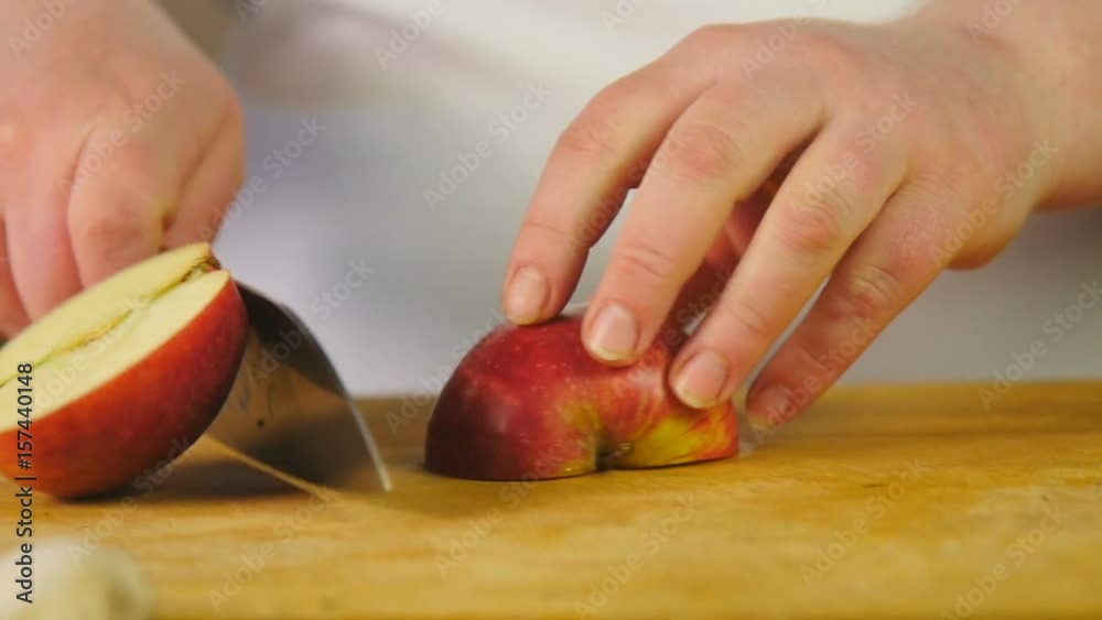 Side view chef cuts red apple into half-rings on a wooden cutting board Side view chef cuts red apple into half-rings on a wooden cutting board