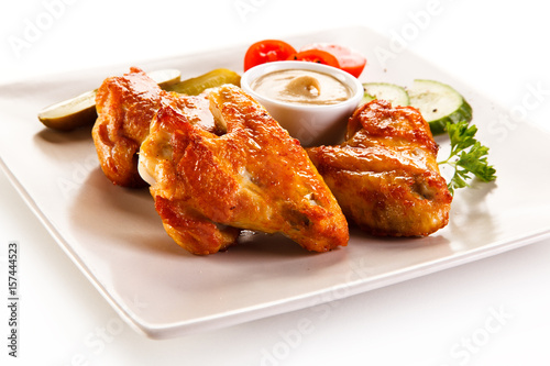 Grilled chicken wings with vegetables on white background