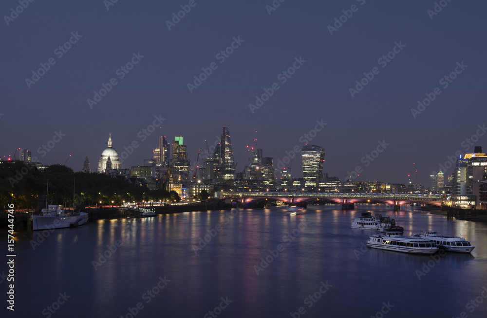 skyscrapers in london city with st paul's cathedral at night seen over thames river