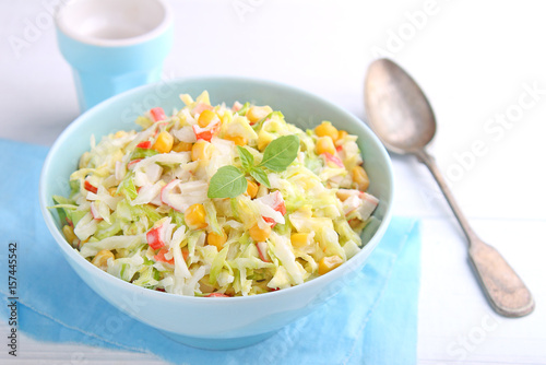 Salad of young cabbage with corn and crab sticks in blue bowl