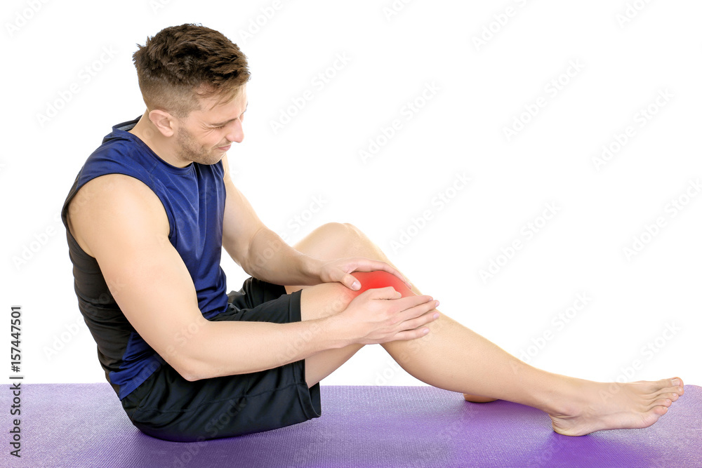 Sporty young man suffering from pain in leg on white background Sporty young man suffering from pain in leg on white background