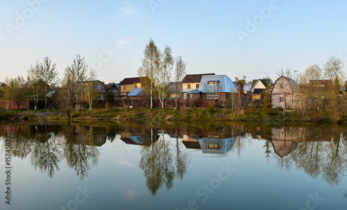 Panorama of village houses in a reflection of the lake at sunset
