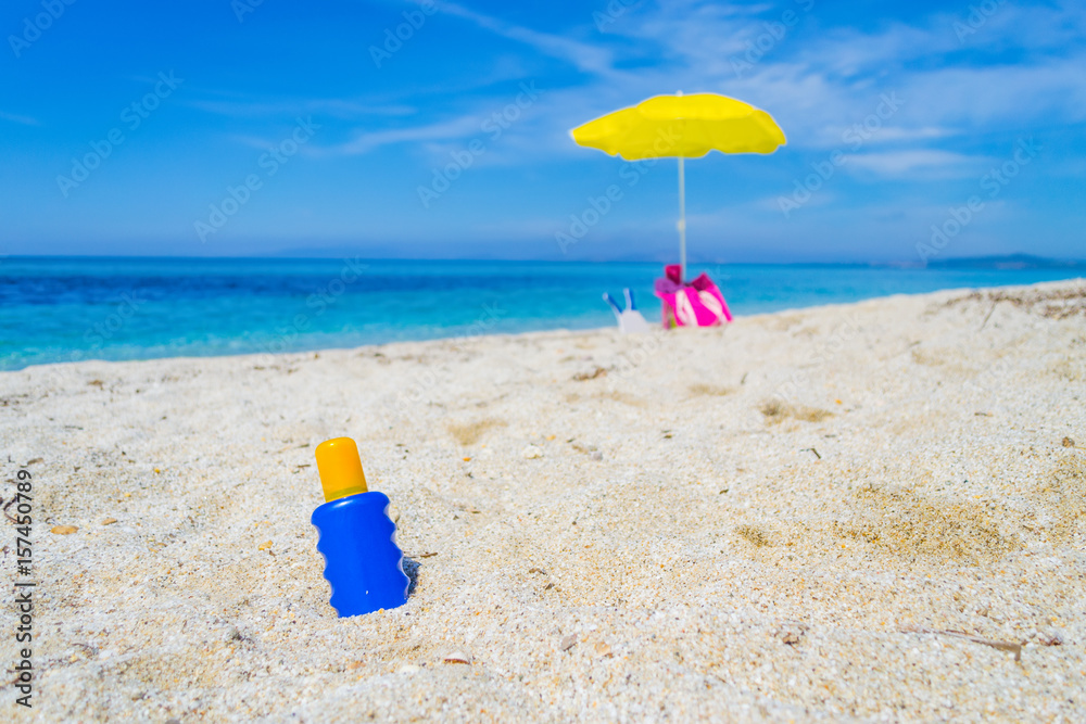 lotion bottle and beach umbrella on the sand lotion bottle and beach umbrella on the sand