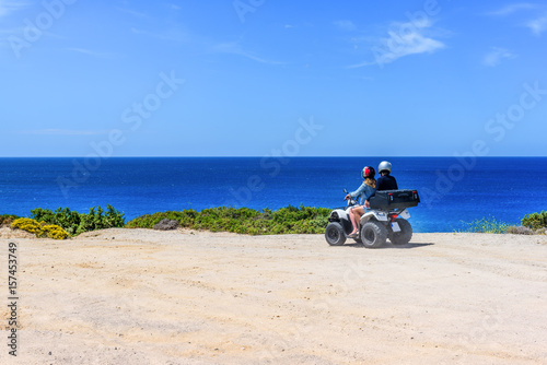 Quadro em tela Young couple on a quad during trip along coast of Milos island, Greece