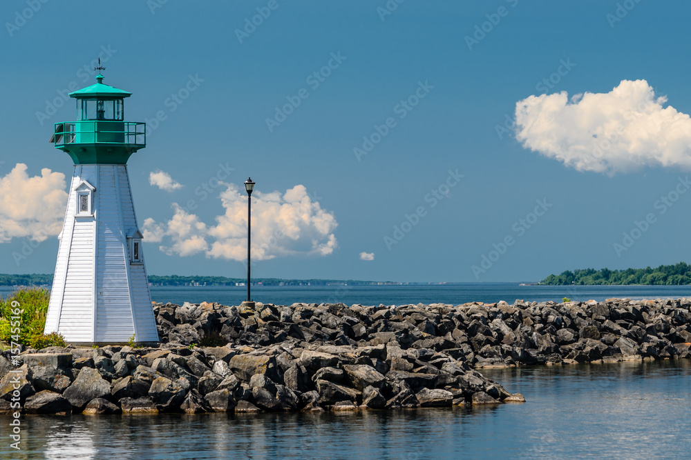 St. Lawrence River lighthouse on a rocky breakwall leading to the right.